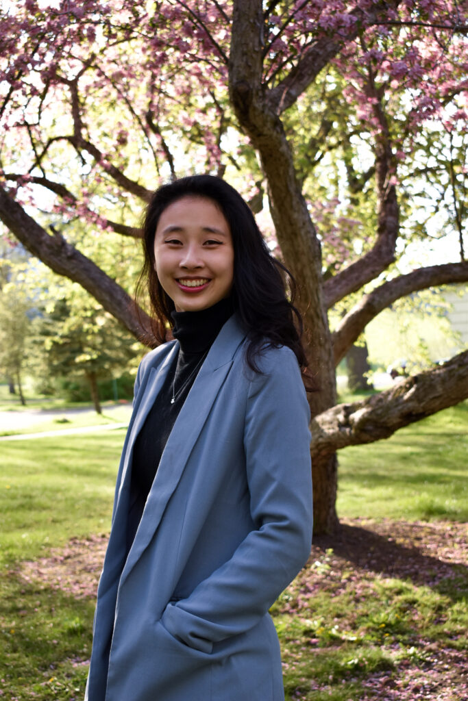 Image of Jenny Chuang standing in front of a blooming tree in spring